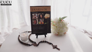 Invitación de funeral elegante en exhibición con vela, rosario y flores blancas, diseño negro y dorado con collage de fotos, plantilla editable en Canva ideal para honrar la memoria de un ser querido / Elegant funeral invitation displayed with candle, rosary and white flowers, black and gold design with photo collage, editable Canva template perfect to honor a loved one